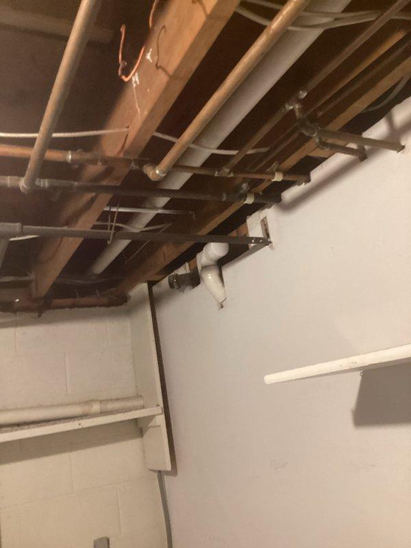 Completed full HVAC system installation in residential basement mechanical room, including new furnace unit with PVC condensate drain and venting lines, air conditioning system with metallic supply ductwork and vertical exhaust venting, and integrated piping infrastructure with copper and PVC components properly secured to floor joists with approved hangers and brackets.