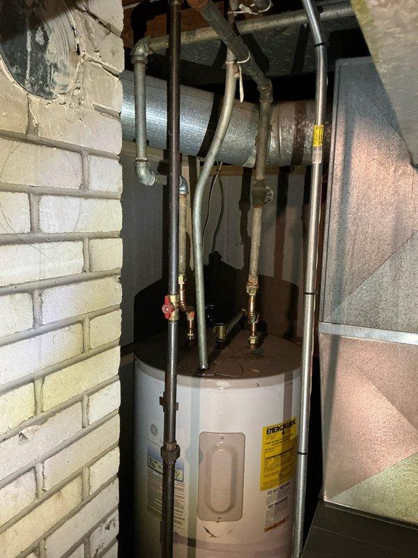 Responded to service call for water heater producing lukewarm water with no visible leaks. Performed comprehensive evaluation of 9-year-old water heater system and inspected all plumbing connections, pressure relief valve, and heating elements. Assessed HVAC system including furnace and air conditioning equipment in utility area. Documented equipment conditions through photographic records showing water heater installation with copper piping connections, pressure relief valve, and associated ductwork. Provided customer with detailed repair versus replacement options through Guard Home Warranty to address temperature maintenance issues.