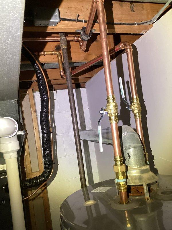 Completed water heater repair in residential utility room. Serviced plumbing connections, inspected copper supply lines, brass valves, and associated piping system to restore proper operation. All components tested and functioning correctly upon completion.