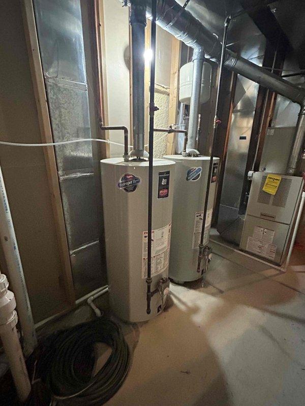 Completed water heater replacement estimate for residential property with existing tank in service for minimum 12 years. Assessed current white cylindrical water heater installation in unfinished basement mechanical room, documenting existing copper piping connections, venting configuration, and proximity to HVAC equipment including furnace and ductwork systems. Photographed equipment specifications, manufacturer labels, and current installation layout to provide accurate replacement recommendations and ensure proper sizing for household hot water demands.