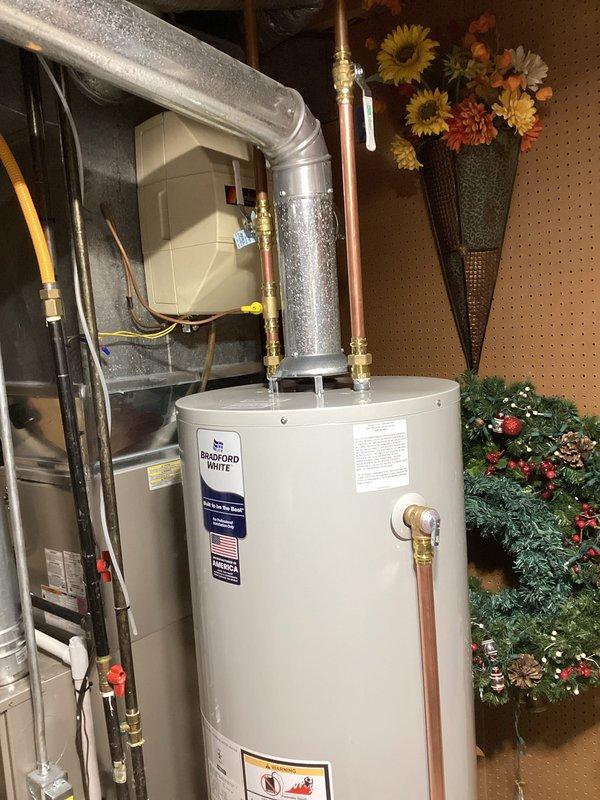 # Water Heater Installation

Successfully completed a residential water heater replacement in a basement utility area. Removed the existing water heater and installed a new Bradford White water heater unit manufactured in the USA. Established all required plumbing connections using copper piping with brass fittings at the top of the unit. Installed pressure relief valve and proper discharge piping to code specifications. Connected hot and cold water supply lines with appropriate shut-off valves for system isolation. Verified all connections for proper sealing and tested for leaks. Ensured the water heater was level and properly positioned on the concrete floor with adequate clearance for ventilation and service access. Connected gas supply line with appropriate safety shut-off valve. Tested all safety controls including temperature and pressure relief valve operation. Filled the tank, purged air from the system, and verified proper heating function. Confirmed all manufacturer specifica