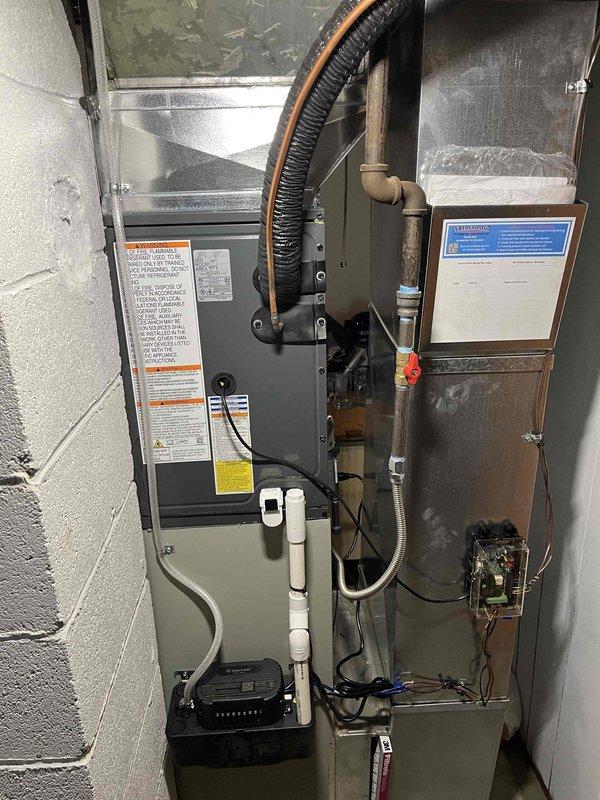 Completed add-on air conditioning installation to existing forced-air heating system in basement utility area. Installed new air handler unit with associated ductwork connections, including flexible supply duct routing and metal plenum integration with existing furnace system. Configured condensate drain lines using PVC piping, established electrical connections and control wiring between new AC components and existing HVAC equipment, and secured all documentation and system specifications on-site for future reference.