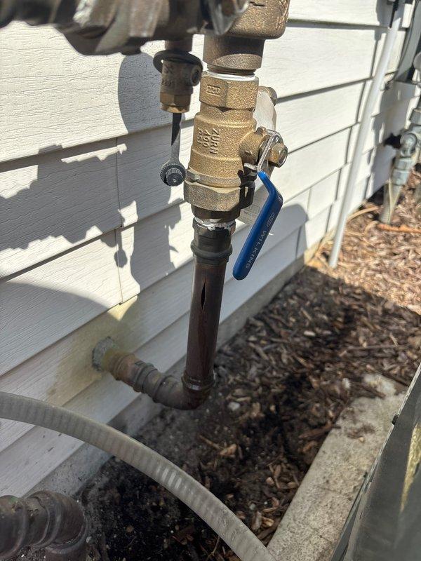 Responded to plumbing leak emergency involving broken pipe on backflow prevention system. Located and accessed exterior shut-off valve at foundation level as directed. Replaced damaged section of copper piping connected to brass ball valve assembly with blue handle. Verified proper operation of backflow preventer and associated brass fittings, ensuring all connections were secure and leak-free. System tested and restored to full operational status.