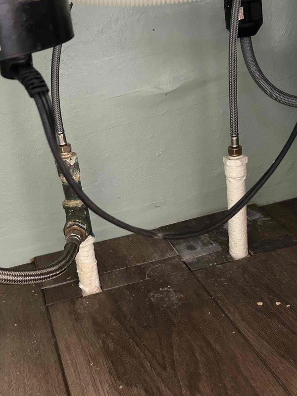Conducted on-site assessment for whole home re-pipe project. Documented existing plumbing infrastructure including corroded water heater connections with visible mineral deposits on metal fittings, braided stainless steel supply lines, and PVC drainage system running through exposed ceiling joists in basement/crawl space area. Photographed current conditions to support comprehensive estimate for complete residential plumbing system replacement.