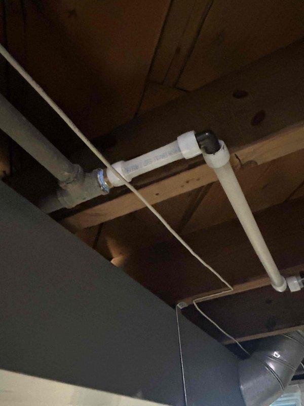 Conducted on-site assessment for whole home re-pipe project. Documented existing plumbing infrastructure including corroded water heater connections with visible mineral deposits on metal fittings, braided stainless steel supply lines, and PVC drainage system running through exposed ceiling joists in basement/crawl space area. Photographed current conditions to support comprehensive estimate for complete residential plumbing system replacement.