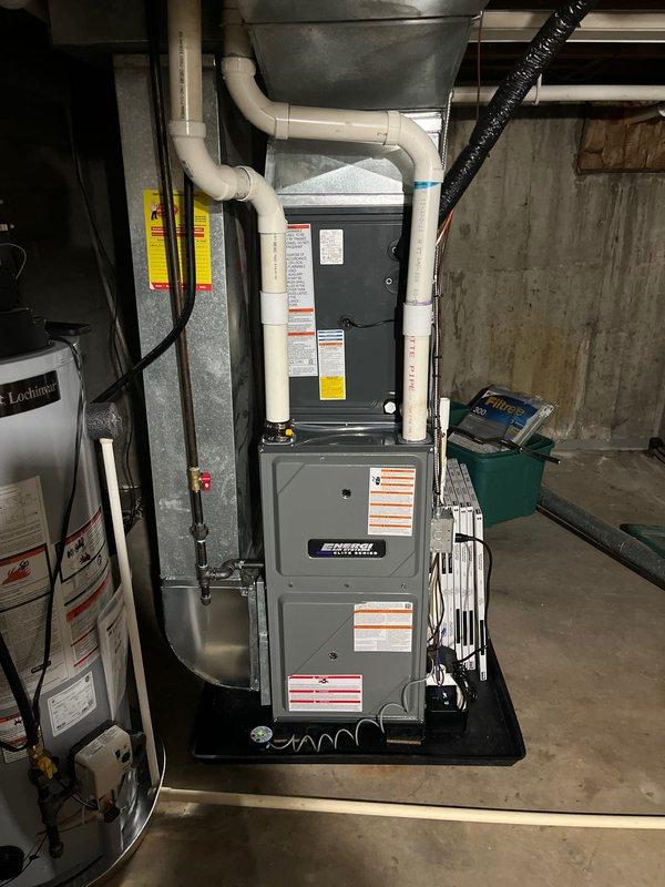 Completed full HVAC system replacement including new furnace and air conditioning unit in basement utility area. Installed black vertical air handler with pleated air filter, connected all necessary PVC condensate drainage lines, refrigerant lines, and electrical connections per manufacturer specifications. System tested and verified operational with all safety controls functioning properly.