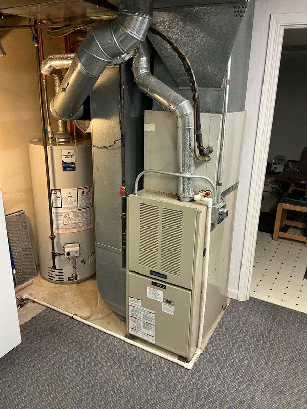 Conducted sales estimate for replacement of 30-year-old residential forced air furnace system currently operational in utility closet. Documented existing beige furnace unit with galvanized metal ductwork, adjacent water heater, and overall mechanical room configuration through photographic assessment to provide comprehensive replacement proposal for aging HVAC equipment.