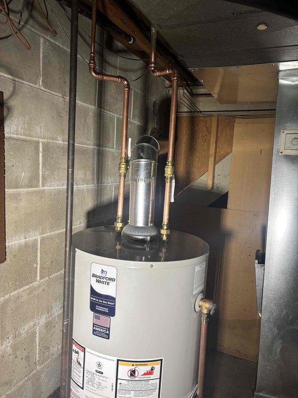 Completed installation of a 40-gallon Bradford White natural gas water heater (Model RG240S6N) with 40,000 BTU/hr input rating. Connected copper supply lines with brass fittings to inlet and outlet ports, installed expansion tank on top of unit, and verified proper venting configuration. All connections tested and unit operational per manufacturer specifications.