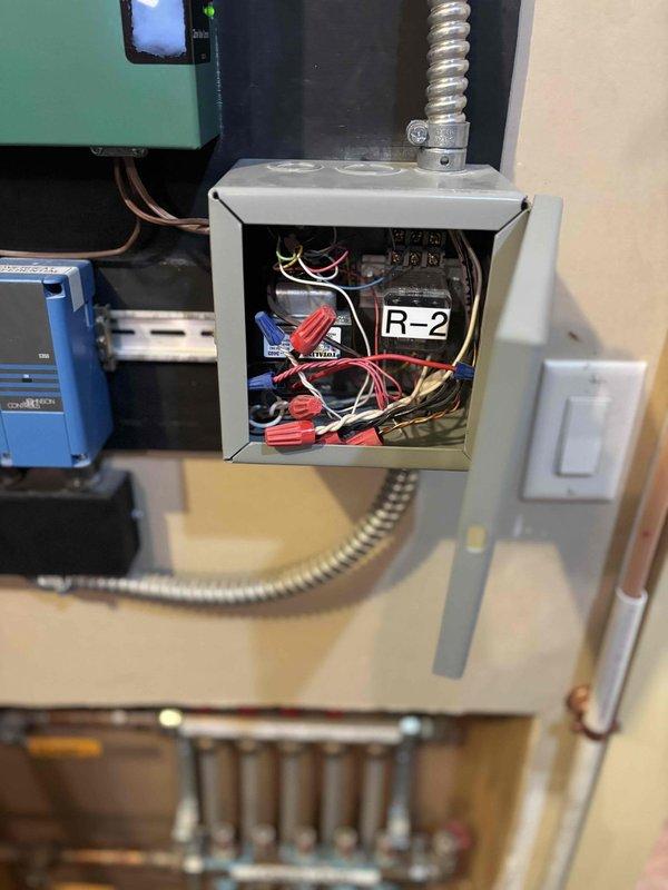 Responded to complaint of extremely hot boiler room and piping on new Lochinvar WT 02-2036 boiler installation. Inspected overheat control system including R-2 relay, transformer, and associated wiring in junction box. Documented control panel configuration, electrical connections, and system components with photos to assess potential installation issues causing excessive heat conditions.