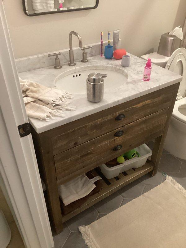 Completed comprehensive plumbing project estimate for residential property including bathroom vanity replacement, outdoor spigot replacement, and additional plumbing tasks. Assessed existing bathroom featuring rustic barn-wood style vanity with white marble countertop, undermount sink, and brushed nickel fixtures, as well as current water treatment system installation including blue pressure tank, filtration components, copper and PVC piping with brass fittings, and stainless steel storage tank. Provided detailed evaluation and recommendations for vanity replacement, exterior hose bib installation, and supplementary plumbing work requested.