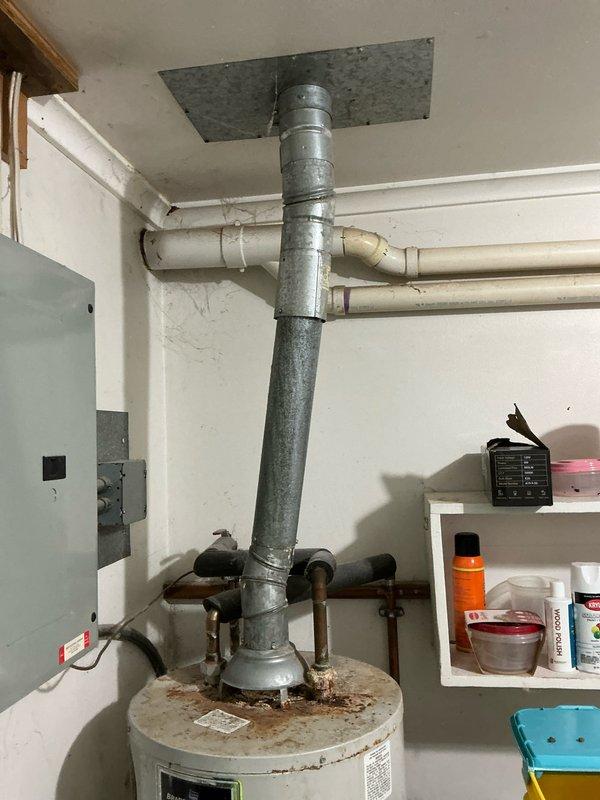 Conducted on-site assessment of an eleven-year-old water heater showing significant signs of aging and deterioration. Documented extensive rust corrosion on tank top surface, oxidized copper supply piping with greenish-blue patina, and weathered galvanized exhaust venting system. Provided comprehensive estimate for complete water heater replacement and installation, including removal of existing unit, proper disposal, and installation of new equipment with code-compliant connections and venting.