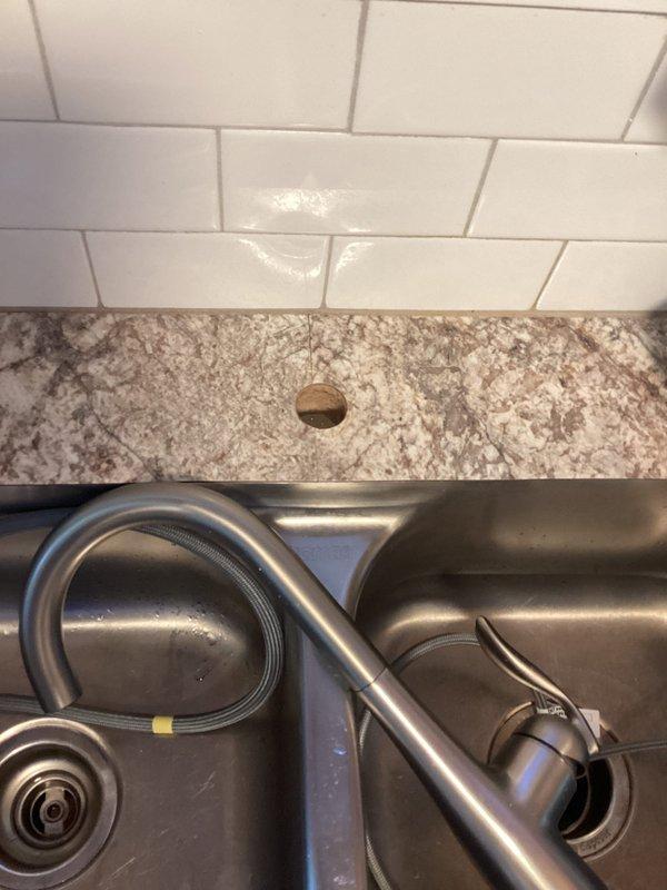 Completed installation of customer-supplied Moen Classic kitchen faucet in approximately 90-year-old residential property. Removed defective faucet that had been causing leak at sink location. Installed new Moen pull-down spray faucet with brushed nickel finish on double-basin stainless steel sink. Connected water supply lines, verified proper operation of pull-down spray head and handle controls, and tested for leaks. New faucet is fully functional with no active leaks detected.