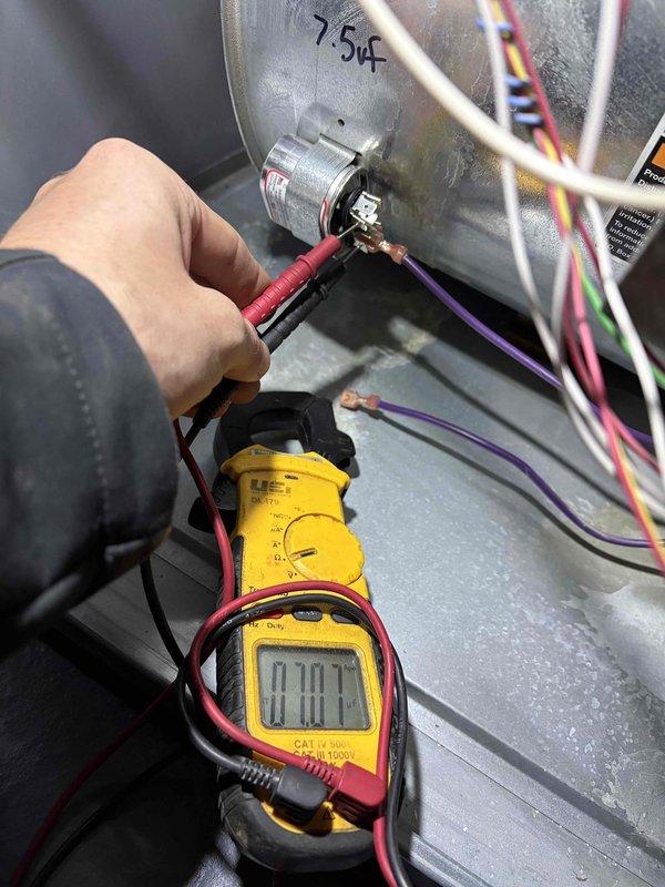 Completed annual cooling maintenance on 2011 Lennox AC system. Performed comprehensive system inspection and testing of 18-year-old unit. Noted outdoor disconnect box has inoperable handle with handwritten warning indicating broken handle requiring use of interior breaker for system shutoff. Conducted electrical diagnostics using digital multimeter, measuring capacitor performance which showed 0.117 reading on 7.5µF rated component indicating potential capacitor degradation. Inspected all electrical connections, wiring, and components within air handler. Documented existing conditions with photos for service records. System operational at time of departure with notation of disconnect box safety concern requiring future attention.