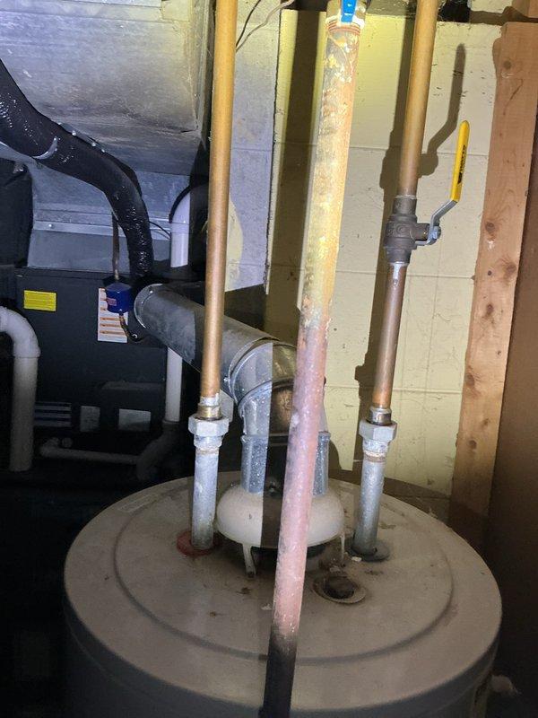 Provided estimate for water heater replacement in basement utility area. Assessed existing A.O. Smith ProMax water heater with connected copper supply lines, galvanized piping, and metal flue vent. Documented current installation configuration including proximity to HVAC equipment, existing plumbing connections with yellow-handled shut-off valve, and PVC drainage piping. Photographed equipment specifications and mechanical room layout for proposal preparation.