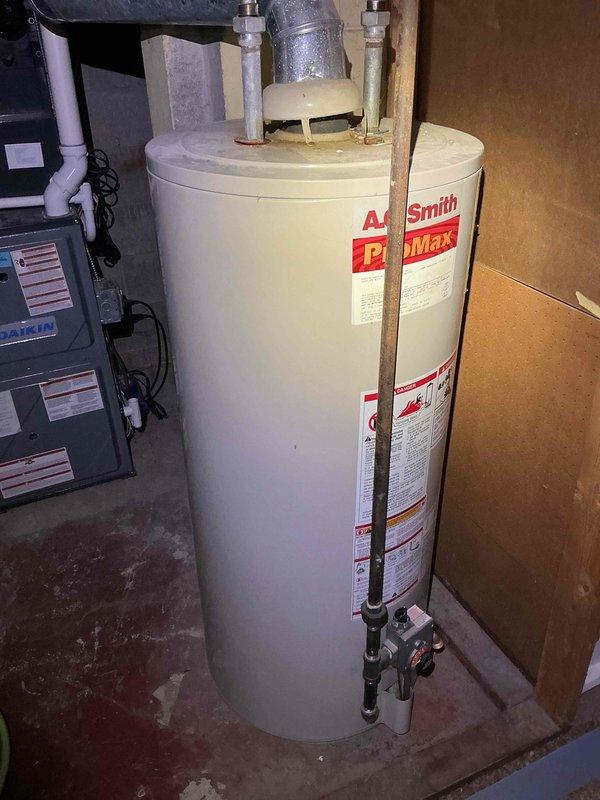 Provided estimate for water heater replacement in basement utility area. Assessed existing A.O. Smith ProMax water heater with connected copper supply lines, galvanized piping, and metal flue vent. Documented current installation configuration including proximity to HVAC equipment, existing plumbing connections with yellow-handled shut-off valve, and PVC drainage piping. Photographed equipment specifications and mechanical room layout for proposal preparation.