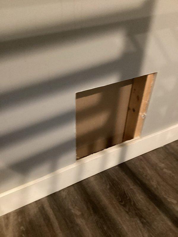 Responded to downstairs bathroom odor complaint with suspected toilet venting issue. Conducted inspection of toilet installation and surrounding plumbing system. Created access panel in drywall adjacent to toilet to assess drain and vent pipe condition for potential leaks. Inspected exposed framing and plumbing connections behind wall cavity. Documented conditions with photographs showing access point and bathroom fixtures. Issue reported as improved by occupant; further evaluation of venting system may be required pending findings from wall cavity inspection.