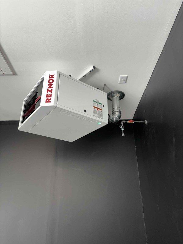 Installed new Reznor unit heater in corner-mounted ceiling configuration. Connected gas supply line with appropriate shut-off valve and completed all electrical and ventilation connections. Verified proper operation of heating elements and controls upon startup.