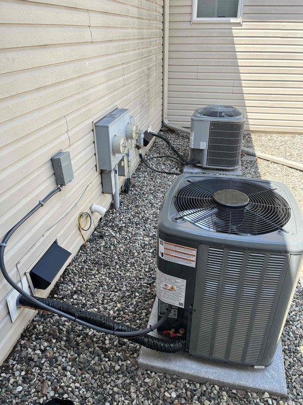 Completed full air conditioning system installation at residential property. Installed two new condenser units on concrete pads in narrow side yard access area between structures, mounted electrical disconnect boxes and conduit on exterior wall, and ran refrigerant lines from outdoor units to interior air handlers. All components properly positioned, secured, and connected per manufacturer specifications with system tested and operational upon completion.