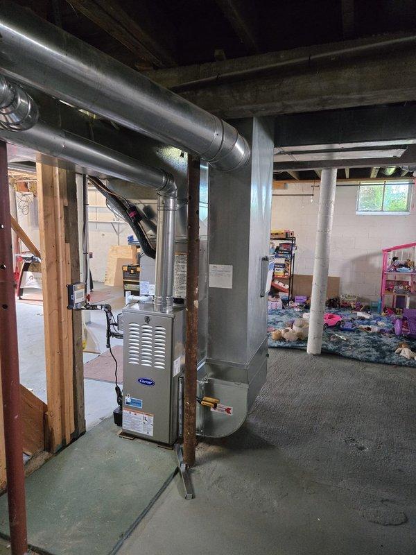 Successfully completed full HVAC system replacement in basement location, installing new Carrier brand furnace and air conditioning system. Removed existing equipment and installed modern high-efficiency units with complete ductwork integration, including new metallic supply and return ducts with proper transitions and elbows throughout the space. Configured air handler unit with vertical mounting in metal frame structure, connected all ductwork sections with proper sealing, and ensured proper clearances from structural elements and concrete walls. Verified all electrical connections, tested system operation for heating and cooling functions, and confirmed proper airflow throughout the distribution system. All installation work completed to manufacturer specifications and local code requirements, with system fully operational and ready for service.
