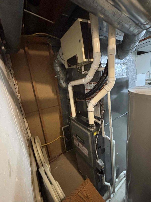 Completed full residential air conditioning system installation including outdoor condenser unit and indoor air handler. Outdoor unit was positioned on concrete pad in side yard with proper clearances maintained, PVC condensate drainage lines installed and secured to building exterior. Indoor equipment installed in basement mechanical area with new flexible ductwork connections, PVC piping for drainage and venting, and all electrical connections completed per manufacturer specifications. System tested and verified operational upon completion.