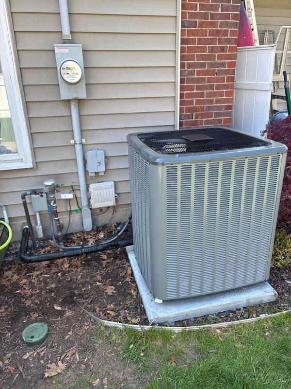 Completed full HVAC system replacement including outdoor condensing unit and indoor air handler/furnace. Installed new beige/tan condenser unit on existing concrete pad at side of residence with proper electrical disconnect and condensate drainage. Connected refrigerant lines and verified proper charge levels. Inside mechanical room, installed new dark gray furnace unit with complete ductwork connections and secured metallic supply/return ducts. Verified all gas connections, electrical wiring to both indoor and outdoor units, and tested system operation. System startup successful with proper airflow, temperature differential, and all safety controls functioning as designed.
