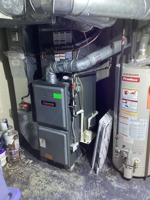 Completed full HVAC system replacement including outdoor condensing unit and indoor air handler/furnace. Installed new beige/tan condenser unit on existing concrete pad at side of residence with proper electrical disconnect and condensate drainage. Connected refrigerant lines and verified proper charge levels. Inside mechanical room, installed new dark gray furnace unit with complete ductwork connections and secured metallic supply/return ducts. Verified all gas connections, electrical wiring to both indoor and outdoor units, and tested system operation. System startup successful with proper airflow, temperature differential, and all safety controls functioning as designed.