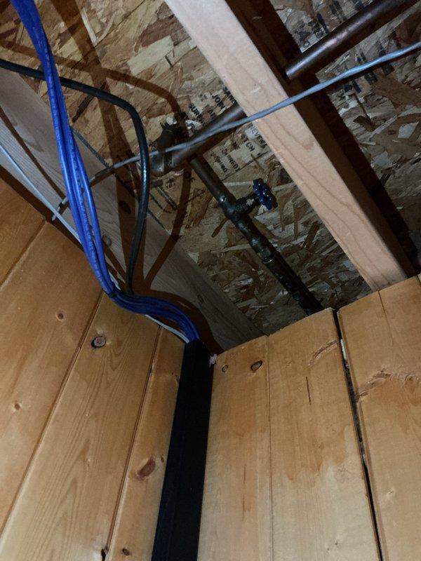 Responded to a leaking front exterior faucet at a thirty-year-old residential property. Upon inspection, accessed the interior plumbing system through the basement ceiling area where blue PEX supply lines and shut-off valves were located. Identified the source of the leak and performed necessary repairs to the faucet assembly. Inspected the exterior wall penetration point where the faucet connects through the siding, noting debris accumulation in the nearby gutter system that was cleared to prevent future drainage issues affecting the faucet area. Tested the repaired faucet for proper operation and confirmed no further leakage. Documented the plumbing configuration and repair work with photographs for service records.