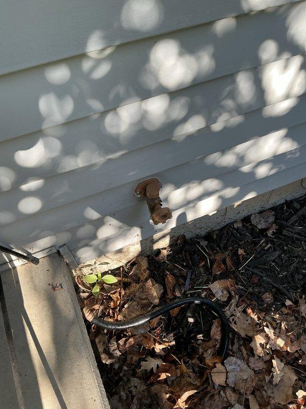 Responded to a leaking front exterior faucet at a thirty-year-old residential property. Upon inspection, accessed the interior plumbing system through the basement ceiling area where blue PEX supply lines and shut-off valves were located. Identified the source of the leak and performed necessary repairs to the faucet assembly. Inspected the exterior wall penetration point where the faucet connects through the siding, noting debris accumulation in the nearby gutter system that was cleared to prevent future drainage issues affecting the faucet area. Tested the repaired faucet for proper operation and confirmed no further leakage. Documented the plumbing configuration and repair work with photographs for service records.
