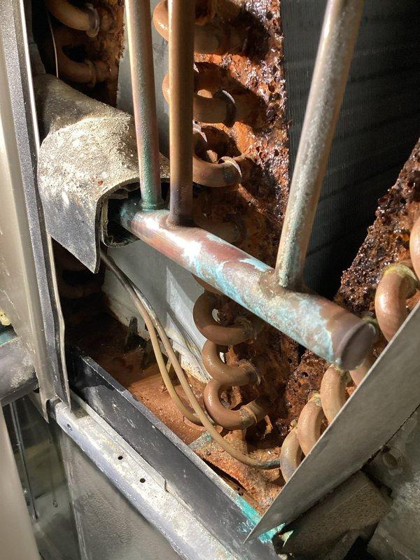 # AC Annual Cooling Maintenance Visit

Completed annual cooling system maintenance on 15-year-old air conditioning unit. Performed comprehensive system inspection and documentation. During inspection, identified severe corrosion and rust deterioration on interior cabinet components, including copper refrigerant lines, mounting brackets, and metal framework. Heavy oxidation noted on horizontal piping with greenish patina formation, indicating prolonged moisture exposure. Cabinet structural integrity compromised due to extensive rust penetration causing metal flaking and pitting. Verified zone damper actuator operation and mounting integrity in ductwork system. Documented all findings with photographic evidence for customer records and future service recommendations.