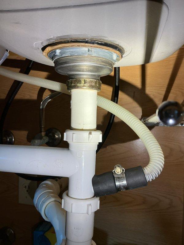 Responded to service call for water leak under sink. Upon inspection, identified leak at sink drain flange connection where chrome fitting meets basin. Assessed P-trap assembly and drain connections for additional leak points. Tightened slip-joint connections on white PVC P-trap assembly and secured corrugated drain hose with metal hose clamp. Verified all plumbing connections were properly seated and sealed. Tested drain system for proper flow and confirmed leak was resolved with no additional water seepage detected.