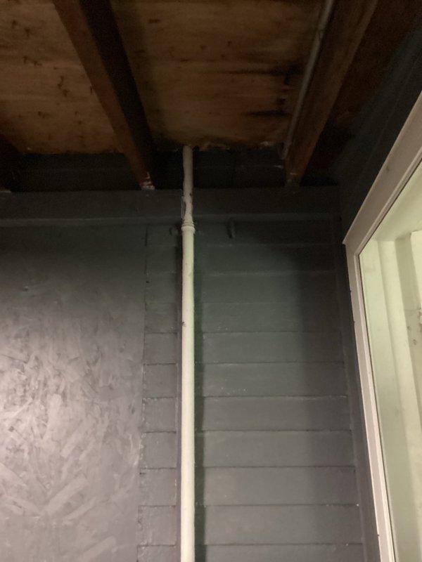 Conducted electrical assessment and provided estimate for 96-year-old residential property following recent inspection findings. Evaluated existing exterior electrical meter assembly mounted on dark gray horizontal siding with white conduit system and visible inspection tag. Assessed interior electrical infrastructure including exposed basement/crawl space areas with aging electrical components and PVC conduit routing through wooden joists. Documented current electrical panel condition, meter configuration, and overall system integrity to determine scope of work required for electrical box replacement and additional necessary upgrades to bring installation into compliance with current code requirements.