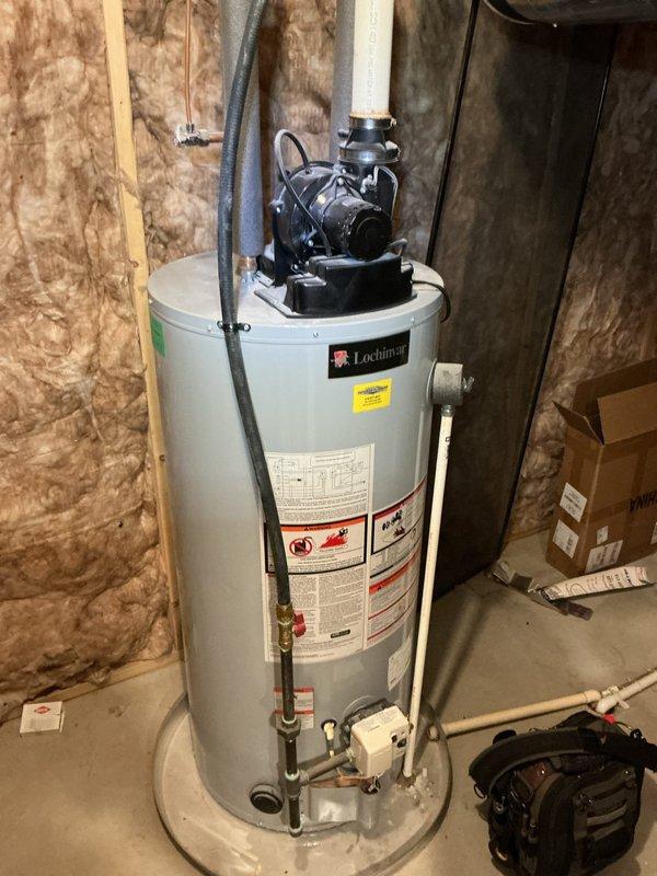 Responded to no cooling complaint on residential HVAC system. Upon arrival, found furnace and humidifier installation in basement utility area with Lochinvar water heater present. Conducted diagnostic evaluation of system blowing room temperature air. Inspected furnace unit, humidifier assembly with vertical metal ductwork, and associated electrical connections including conduit wiring. Verified all mechanical components, plumbing connections, and vent piping configurations. Documented equipment condition and installation setup with photographic records for service file. System age confirmed at less than 10 years old.
