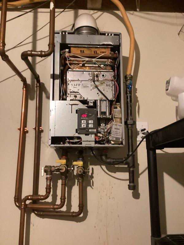 Responded to service call regarding gas odor detected from 12-year-old Rinnai tankless water heater when washing machine was operated. Performed comprehensive inspection of unit with cover removed, examining internal components including copper heat exchanger coils, electronic control boards, wiring, and digital display. Inspected all gas connections including flexible gas line, copper water supply lines, brass shut-off valves, and exhaust venting system for leaks or deterioration. Checked internal valve assemblies, braided water lines, and pressure components for proper operation and signs of wear. Documented unit condition with detailed photography showing internal mechanical components and overall installation. Recommended system flush due to age and maintenance history to address potential sediment buildup that may be contributing to operational issues.