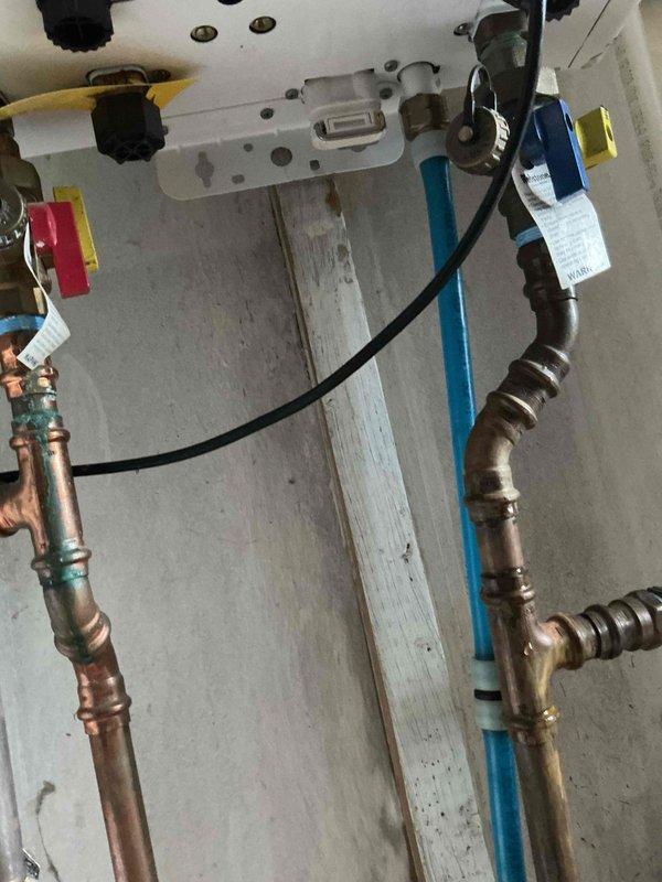 Responded to service call for reported water heater and kitchen sink leaks. Upon inspection, discovered active leak at Navien tankless water heater installation with moisture present on copper supply lines and connections. Investigated kitchen sink leak and found significant water damage behind wall cavity with extensive mold growth on drywall and framing members. Removed wall panel section to expose copper supply lines with compromised valve fittings showing signs of chronic leakage. Documented conditions with photographs showing deteriorated insulation, mold contamination on wall studs, and compromised plumbing connections. Identified need for mold remediation, drywall replacement, and repair of leaking copper pipe connections and valve assemblies at both water heater and under-sink locations.