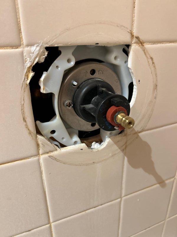 Responded to plumbing leak call initially reported as HVAC-related but determined to be caused by frozen and broken exterior spigot. Accessed shower valve assembly through wall opening to diagnose hot water delivery issue, inspecting valve stem, mounting hardware, and connection points. Documented condition of plumbing fixtures and identified frozen pipe damage as primary cause of leak, unrelated to water heater system.