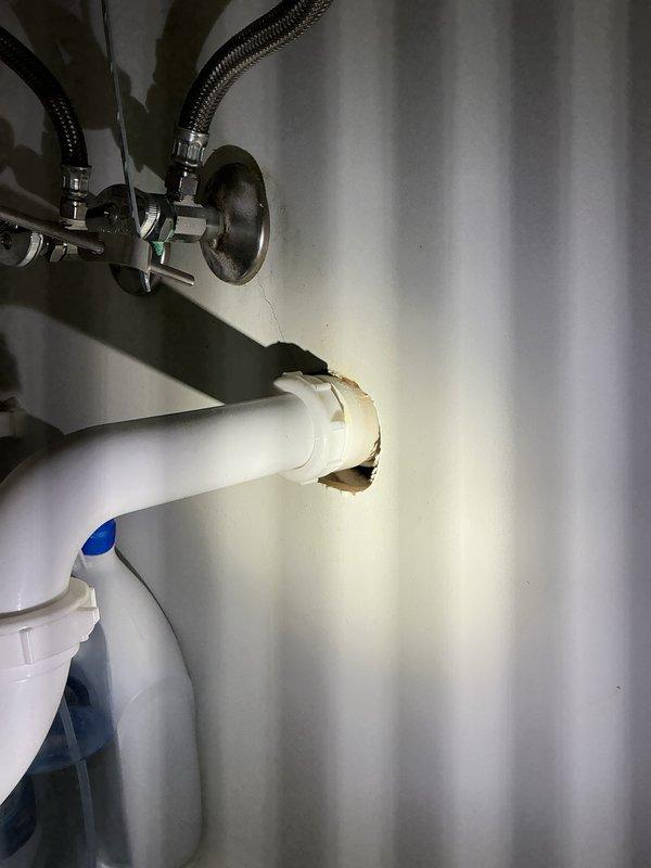 Completed comprehensive Plumbing Club Inspection documenting existing plumbing conditions. Identified and photographed damaged white PVC pipe with visible break and rough torn edges in utility area, along with metal plumbing fixture assembly featuring braided flexible hoses. Documented sump pump installation including basin cover, discharge piping, and associated PVC plumbing components in basement area for maintenance records.
