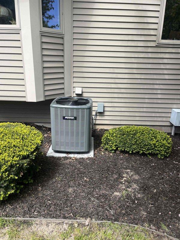 Complete HVAC system installation performed at residential property. Installed new Carrier furnace unit in basement utility area with corresponding ductwork configuration, including galvanized metal supply ducts with proper support strapping and elbow transitions. Exterior condensing unit positioned on concrete pad against house exterior with tan vinyl siding, connected via refrigerant lines and electrical conduit routed to interior equipment. Air handler cabinet installed adjacent to furnace with electrical junction box mounted and properly wired. All equipment secured, leveled, and tested for proper operation. System commissioned and verified operational parameters within manufacturer specifications.