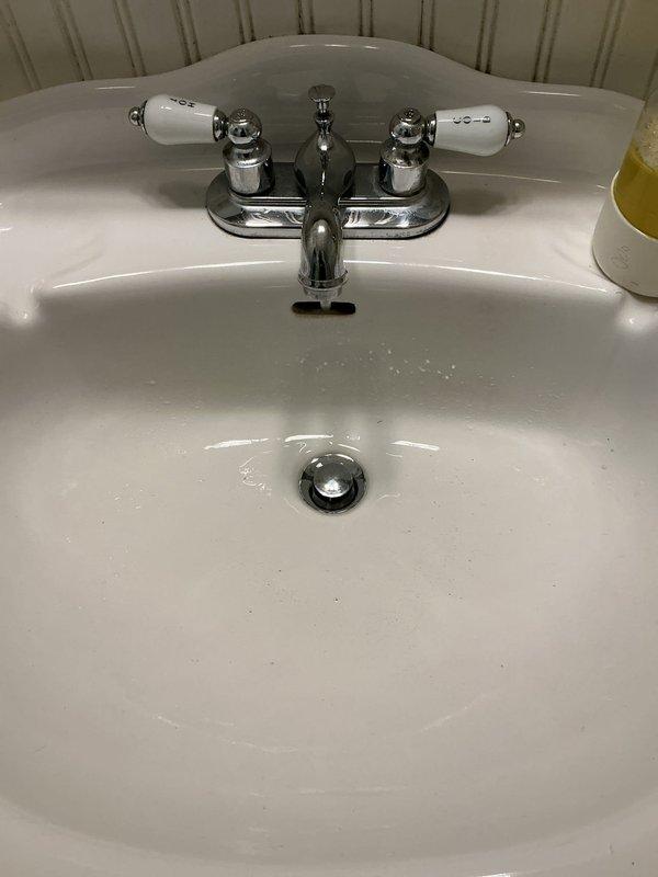 Responded to main bathroom for leaking faucet repair. Upon inspection, identified leak at traditional two-handle chrome faucet with porcelain handle inserts on white oval sink. Disassembled faucet handles, replaced worn cartridges and seals, reassembled unit, and tested both hot and cold water lines to confirm leak was eliminated and proper operation restored.