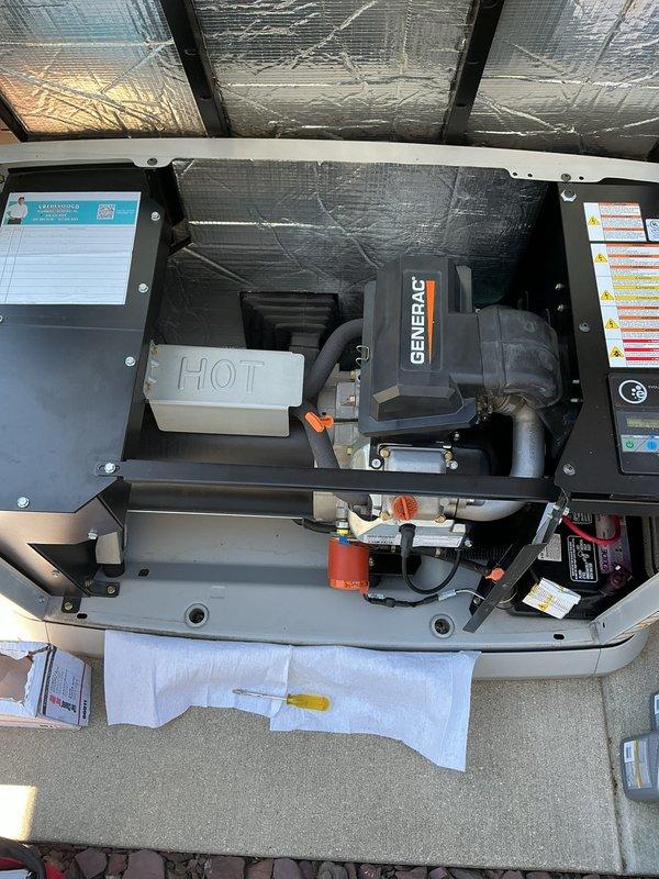 Completed annual preventative maintenance and tune-up on 11-year-old Generac generator unit. Performed comprehensive inspection of engine compartment, verified all internal components, checked fuel system including fuel cap and tank, inspected electrical connections and wiring harnesses, examined cooling system and exhaust assembly with clamps, and reviewed all safety labels and specifications. All components found in good operational condition with normal wear patterns. Unit photographed for service documentation.