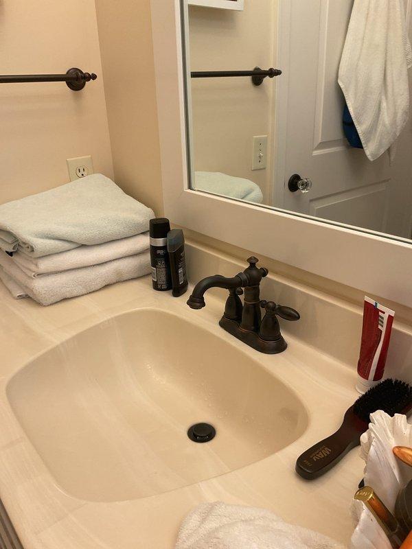 Responded to service call for bathroom faucet repair at vanity sink with dual-handle oil-rubbed bronze fixture. Upon inspection, identified loose faucet mounting requiring tightening and stabilization at countertop. Accessed under-sink cabinet area and assessed plumbing configuration, noting existing water damage staining on cabinet floor from previous moisture issues. Secured faucet assembly, tightened mounting hardware, and verified proper operation of both hot and cold water handles. Tested water flow and checked for leaks at supply line connections and P-trap assembly. Confirmed fixture stability and proper drainage function upon completion.