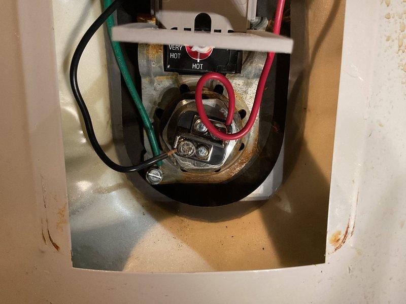 Responded to complaint of insufficient hot water and rapid depletion after recent thermostat installation. Inspected Bradford White RE350S6-1NCWM 50-gallon electric water heater. Documented unit specifications showing 240V/208V operation with dual 4500W/3500W heating elements. Examined upper thermostat installation and wiring connections in control compartment. Verified proper wire terminations including black, green ground, and red power wires secured to thermostat assembly. Noted visible corrosion and rust staining in control compartment indicating age-related deterioration and potential moisture exposure. Photographed unit nameplate data and internal thermostat configuration for service records.