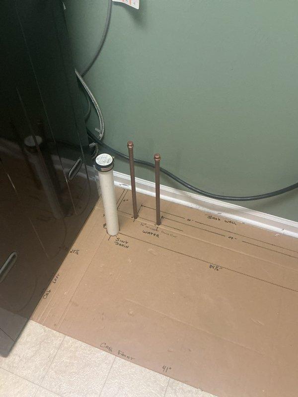 Plumber returned to complete installation of drain line and water line upstairs for new sink location. Installed white PVC drain line routing vertically through floor cavity, terminating at appropriate height above cabinet floor level to accommodate P-trap assembly with adjustment capability for final fixture connection. Ran copper water supply lines with proper fittings and elbows from lower level through structural framing to upper floor sink location. All piping secured to wooden joists and framing members per code requirements. Work completed in approximately four hours as scheduled continuation of previous rough-in work.
