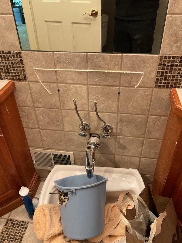 Responded to plumbing leak emergency at residential property. Upon arrival, assessed kitchen sink leak originating from faucet area and shut-off valve beneath sink. Inspected under-cabinet plumbing configuration including garbage disposal unit, P-trap assembly, and supply lines. Placed collection container to monitor active leak and prevent water damage to cabinet interior. 

Proceeded to basement bathroom where additional sink repair was required. Evaluated wall-mounted plumbing fixtures and supply lines. Positioned collection bucket beneath exposed piping to contain water flow during assessment and repair process. Completed necessary repairs to both kitchen and basement bathroom plumbing systems, restoring proper function and eliminating leaks at all affected fixtures.