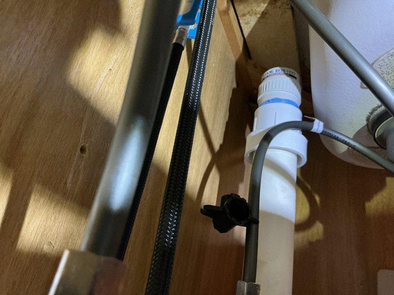 Responded to service call regarding black particles coming from tub faucet when using hot water. Inspected water heater and plumbing system throughout the property. Located deteriorating dip tube inside water heater tank, which was breaking apart and sending plastic fragments through the hot water lines to fixtures. The issue was isolated to the tub faucet as it receives the highest concentration of particulate due to water flow patterns. Documented plumbing connections under sink and crawlspace area showing water heater feed lines and shutoff valves. Advised client that water heater dip tube failure is causing the black particle discharge and recommended water heater replacement due to age and extent of internal component deterioration.