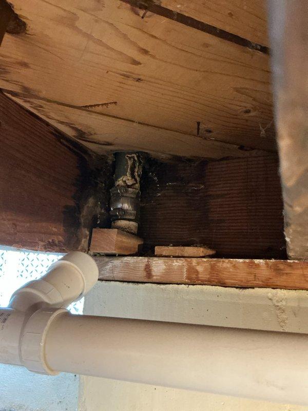 Responded to service call regarding black particles coming from tub faucet when using hot water. Inspected water heater and plumbing system throughout the property. Located deteriorating dip tube inside water heater tank, which was breaking apart and sending plastic fragments through the hot water lines to fixtures. The issue was isolated to the tub faucet as it receives the highest concentration of particulate due to water flow patterns. Documented plumbing connections under sink and crawlspace area showing water heater feed lines and shutoff valves. Advised client that water heater dip tube failure is causing the black particle discharge and recommended water heater replacement due to age and extent of internal component deterioration.