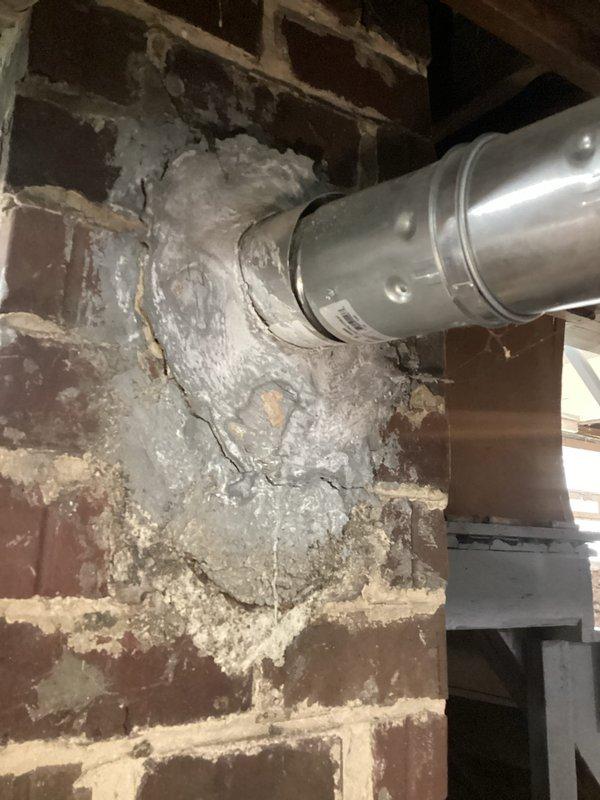 Responded to service call for 15-year-old Bradford White Defender water heater displaying "false pilot flame present" error message. Upon inspection, evaluated unit condition and verified error code. Documented existing installation including copper supply lines, flexible gas connections, and venting system. Assessed chimney and flue condition, noting significant deterioration of masonry with efflorescence, cracked mortar joints, and structural degradation that could impact proper venting function. Photographed water heater installation and compromised chimney structure for customer records. Advised customer of unit's age and overall condition, discussed repair versus replacement options given the existing infrastructure concerns and ongoing error condition. Provided professional recommendations for addressing both immediate water heater issue and deteriorated venting system to ensure safe operation.