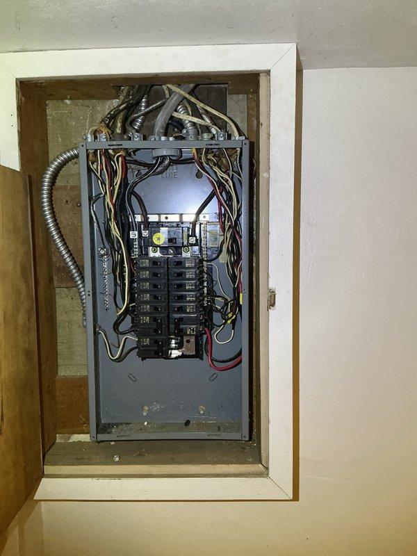 Conducted on-site assessment of 1950s single-family residential property to provide electrical estimate for main service panel upgrade from 100-amp to 200-amp capacity and repair of multiple non-functioning basement outlets. Inspected existing electrical panel installation, documented current breaker configuration and wiring conditions, photographed panel interior showing dual-column breaker arrangement with various circuit conductors, and evaluated service entrance equipment to determine scope of work required for amperage upgrade and outlet repairs in unoccupied home.