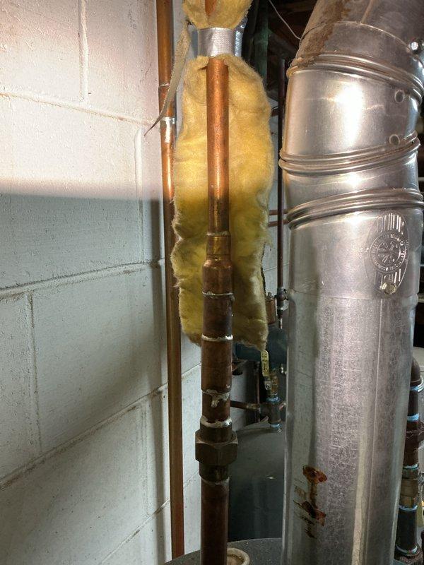 Conducted site assessment for replacement of 15-year-old 40-gallon residential water heater located in basement utility area. Evaluated existing installation including copper supply piping, brass connections, metallic flue vent system with elbow joint, and current configuration within concrete block utility room. Documented current system condition showing age-related wear on tank surfaces and verified standard residential installation requirements for proper replacement specifications. Photographed existing plumbing infrastructure, insulated copper lines, galvanized ductwork, and surrounding mechanical components to prepare accurate replacement estimate for new water heater installation.