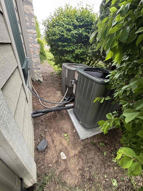Completed full installation of new residential HVAC system including furnace and air conditioning condenser unit. Furnace installed in mechanical room with proper venting via white PVC piping, integrated with AprilAire humidifier system, and connected to existing ductwork. Outdoor AC condenser positioned on concrete pad in side yard with appropriate clearance from structure, refrigerant lines installed with black foam insulation running through exterior wall connection. All equipment properly labeled with manufacturer specifications and safety warnings, system tested and operational.