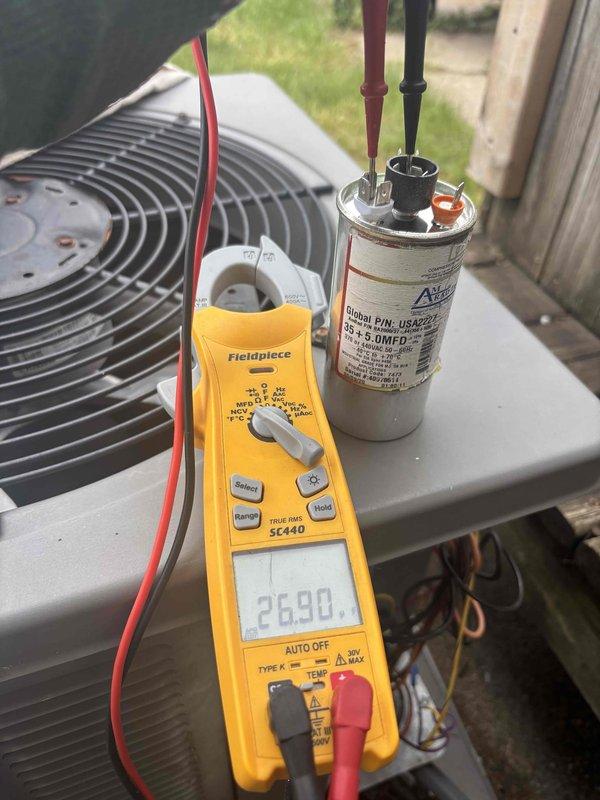 Completed annual cooling maintenance on 13-year-old Rheem AC system. Inspected air handler interior components and refrigerant lines, verified proper operation of condensate float assembly. Tested and documented capacitor performance using digital multimeter, confirming readings within acceptable range at 26.90 microfarads for dual-run capacitor on outdoor condenser unit.